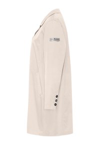 Beige lange jas gezien vanaf de zijkant met drie zwarte knopen op de manchet en een kleine rechthoekige patch op de bovenarm.