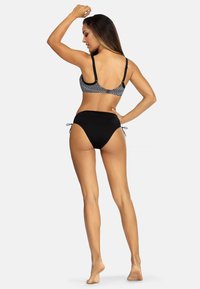 Czarny zestaw bikini z wzorzystym biustonoszem na regulowanych ramiączkach i wysokim dołem z bocznymi troczkami. Gładka faktura, minimalistyczny design.