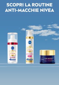 Tre prodotti di skincare anti-macchia Nivea: un siero con pompa in una bottiglia trasparente, un solare fluido con accenti dorati e un barattolo di crema blu con un coperchio dorato.