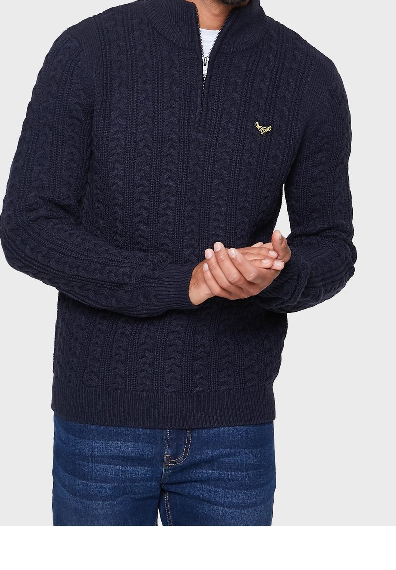 Navy Strickpullover mit Viertelreißverschluss-Kragen, gerippten Ärmeln und Saum sowie einem strukturierten Zopfmuster. Mit einem kleinen Emblem akzentuiert.