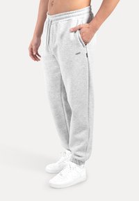 Ljusgrå joggingbyxor i mjukt tyg med elastisk midja och sidofickor. Kombinerade med vita sneakers med texturerad sula.