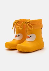 Bottes de pluie en caoutchouc jaunes avec un design de tête de canard, des yeux ronds et un accent orange. Semelle texturée et dessus lacé ajustable pour un bon ajustement.