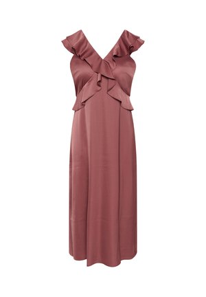 Femme aux cheveux foncés attachés en chignon, portant des boucles d'oreilles en perles et une robe mauve sans manches avec des détails à volants, regardant vers le bas, une main sur la taille.