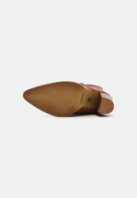 Zapato de cuero marrón con punta afilada, tacón bajo apilado y suela de goma texturada. Presenta costuras sutiles y un acabado suave.