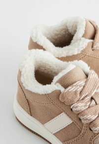 Baskets en daim tan avec doublure en fausse fourrure blanche, bout rond et lacets texturés. Présente une bande latérale blanche contrastante et une semelle en caoutchouc.