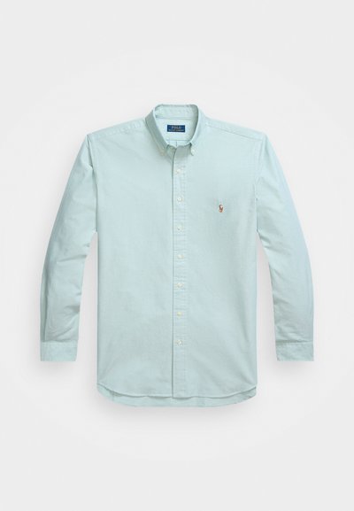 Ανοιχτό μπλε, μακρυμάνικο πουκάμισο με κουμπιά από βαμβακερό ύφασμα και ανοιχτό γιακά. Διαθέτει ένα μικρό κεντημένο λογότυπο στην αριστερή θήκη.