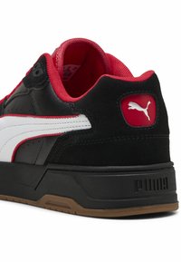 Basket noire et rouge en cuir et daim. Comprend une rayure blanche, un col rembourré et une semelle en caoutchouc avec le logo "PUMA".