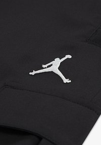 Pantaloncini sportivi neri con logo Jumpman argento, realizzati in tessuto liscio con dettagli cuciti e una tasca laterale.