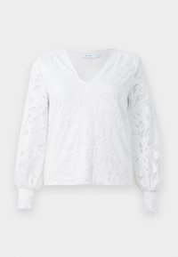 Maglietta bianca a maniche lunghe con scollatura a V, caratterizzata da un design in pizzo floreale testurizzato e polsini arricciati. Realizzata in tessuto leggero.
