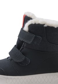 Botín azul oscuro con forro de forro polar en contraste, que cuenta con dos correas de velcro ajustables y una suela de goma texturizada con un patrón de diamante.