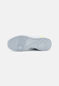 Semelle de chaussure de sport blanche avec des caractéristiques de grip texturé, motifs hexagonaux et un accent circulaire, conçue pour l'adhérence et la durabilité.