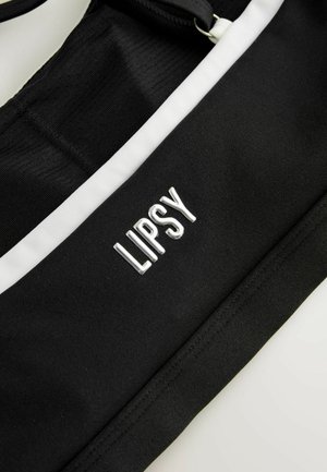 Černý sportovní crop top s bílými akcenty. Má žebrovanou strukturu a stříbrné metalické písmo s logem "LIPSY".