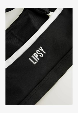 Čierny športový crop top s bielymi akcentmi. Má rebrovanú textúru a logo "LIPSY" v striebornej metalickej farbe.