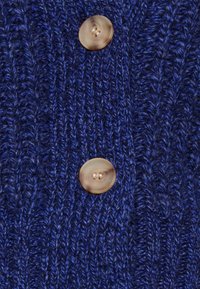 Mörkblå stickad cardigan med ribbad textur och två runda, ljusbruna knappar som detalj fram.