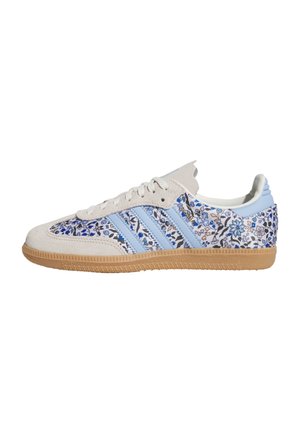 Baskets basses avec embout en daim beige, rayures bleu clair, motif floral bleu sur fond blanc et semelle en gomme.