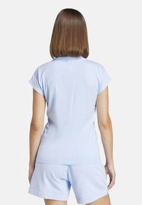 Top azzurro chiaro a maniche corte con collo rotondo, realizzato in materiale morbido, abbinato a pantaloni corti azzurri chiari coordinati. Texture liscia, vestibilità casual.