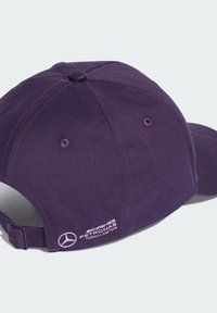 Gorra de béisbol morada hecha de algodón con una correa ajustable. Presenta un logo bordado en el costado y agujeros de ventilación en la parte superior.
