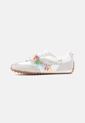 Baskets blanches avec détails en strass, semelle en gomme et une chaîne argentée ornée de breloques en plastique colorées, y compris des cœurs et des étoiles.