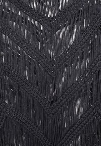Tessuto intrecciato nero con un motivo a zigzag, caratterizzato da lunghe frange e accenti intrecciati, creando un aspetto testurizzato e stratificato.