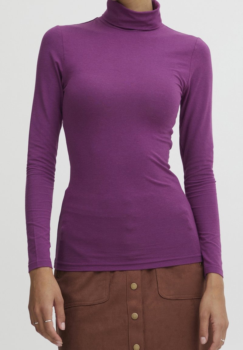 Lila långärmad polotröja tillverkad av mjukt, stretchigt tyg med en figurnära design. Halsringningen är hög och ärmarna är åtsittande.