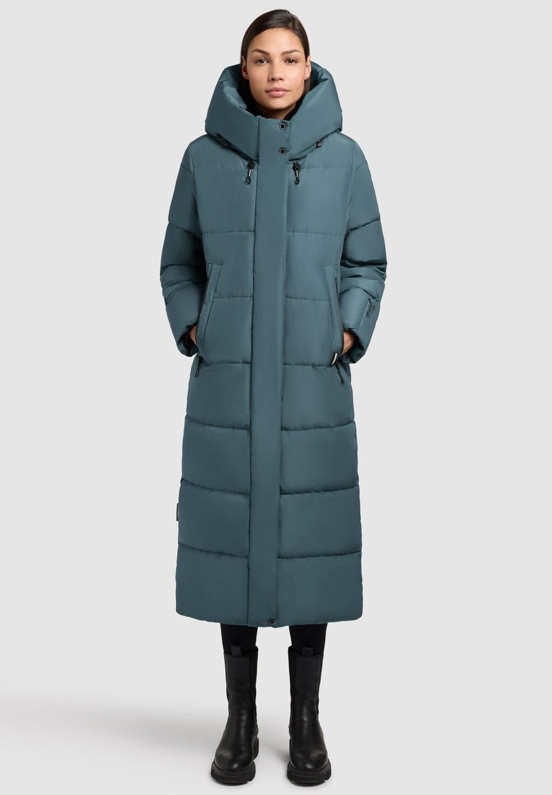 Długi puchowy płaszcz w kolorze morskim, z wysokim kołnierzem i bocznymi kieszeniami. Wykonany z gładkiego, pikowanego materiału o prostej sylwetce.