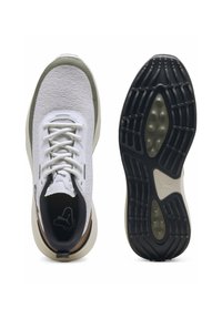 Vita träningsskor med texturerad mesh-ovandel, ljusgröna accenter och en svart gummisula med ett tydligt greppmönster.