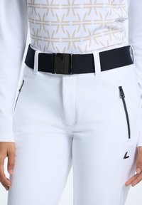 Pantalones deportivos blancos de material elástico, con dos bolsillos laterales con cremallera y un cinturón negro con una hebilla brillante.