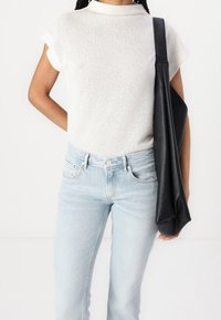 Vitt stickat kortärmat linne, ljusblå denimjeans och en svart strukturerad handväska. Klassisk passform med ett subtilt mönster och avslappnad stil.