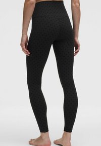 Czarne legginsy z wysokim stanem, o fakturze z subtelnym wzorem kropek, wykonane z elastycznego materiału zapewniającego komfort noszenia i dopasowanie.