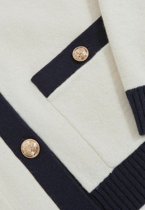 Maglione a maglia in crema e blu navy con tessuto testurizzato, caratterizzato da bottoni dorati e strisce a contrasto lungo i bordi.