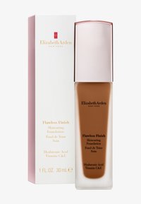 Fond de teint Flawless Finish dans un flacon en verre transparent avec un capuchon métallique rose clair, présenté dans une boîte blanche et rose, ornée de texte doré.