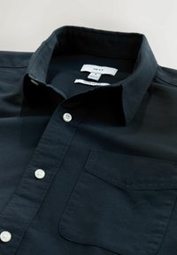 Camicia button-up blu scuro con colletto, bottoni bianchi, una tasca sul petto e etichette che indicano la taglia e la vestibilità. Tessuto liscio.