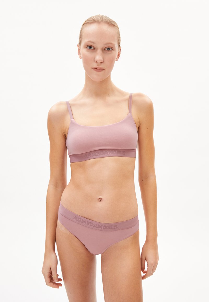 Soutien-gorge rose clair et culotte assortie en tissu doux ; comporte une bande logo sur la taille et de fines bretelles réglables.