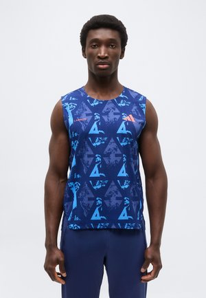 Bărbat cu păr scurt și creț, purtând un tricou sport albastru fără mâneci cu modele geometrice și pantaloni atletici albaștri, stând cu fața înainte.