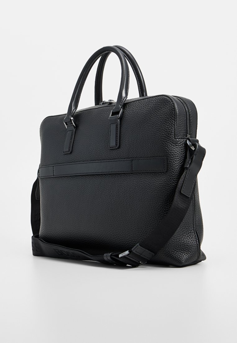 Sac à ordinateur en cuir noir avec une forme structurée, un extérieur texturé, deux poignées supérieures, une bandoulière réglable et une fermeture éclair.