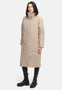 Beige lang frakke med høj krave, frontlukning med trykknapper og sidelommer. Har en glat tekstur og tonalt broderet branding på ærmet.