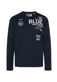 T-shirt a maniche lunghe di colore blu navy in cotone con colletto a girocollo. Presenta grafiche stampate, toppe e accenti di testo bianco. Retro semplice.