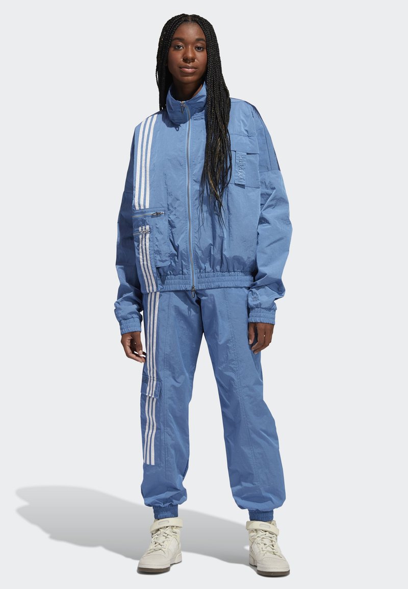 Blauwe sportieve trainingspak met witte strepen, met een zip-up jack met zakken en elastische manchetten, gecombineerd met bijpassende broeken met elastische tailleband.