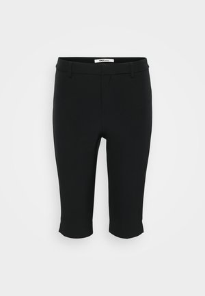 Crne kapri hlače izrađene su od glatkog materijala. Imaju ravni prednji dio s petljama za pojas i skraćeni rub. Jednostavan dizajn bez vidljivih uzoraka.