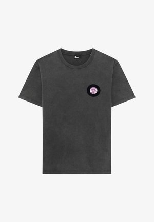 Camiseta de algodão cinza com decote redondo e mangas curtas. Apresenta um pequeno gráfico circular preto no lado esquerdo do peito.
