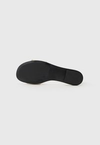 Semelle de chaussure noire avec une texture lisse, une forme légèrement courbée et un talon plat ; aucun motif visible ni détail matériel.