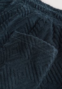 Mörkblå ekologisk handduksset med geometriska mönster, med en mjuk, plyschig yta och ett jämnt vävt mönster.