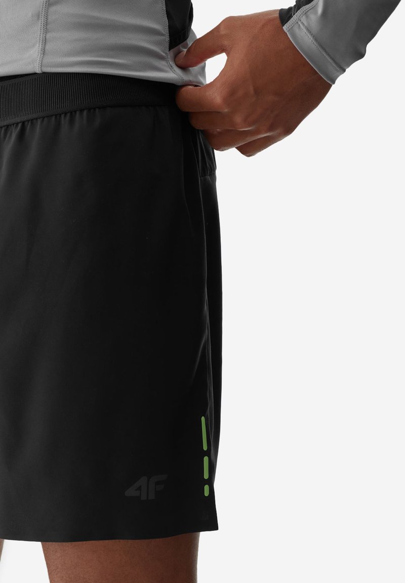 Czarne szorty sportowe wykonane z lekkiego materiału. Posiadają logo i zielone akcenty po bokach. Elastyczna talia dla wygody.