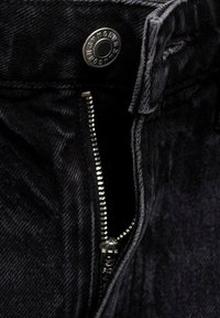 Sorte denimjeans med metalknaplukning og sølvlynlås. Stoffet har en let struktureret finish og mørk syning.