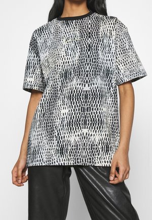 T-shirt met korte mouwen, uitgevoerd in een zwart-wit slangenprintpatroon, met een ronde halslijn en een losse pasvorm. De stof lijkt glad en licht van gewicht.