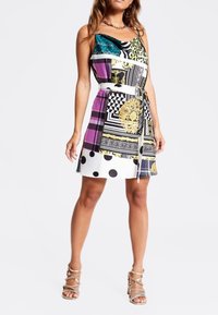 Vestido sin mangas con patrones variados en negro, blanco, púrpura, dorado y verde azulado. Presenta una cintura ceñida y una silueta fluida.