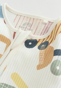 Weißer Strampler aus geripptem Stoff mit einem bunten abstrakten Muster aus verschiedenen Formen, darunter Kreise und Streifen, sowie einem Reißverschluss.