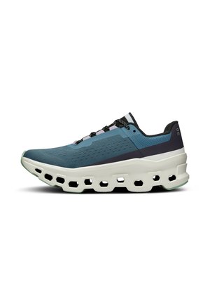 Sneaker featuring a mesh upper in shades of teal and navy, with a thick white sole and hexagonal cutouts for cushioning. Black laces and accents.