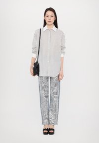 Gestreepte witte blouse, zilveren paillettenbroek, zwarte handtas en platform sandalen met strikdetail. Eenvoudige en moderne ontwerpelementen.