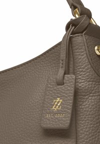 Bolso de mano de cuero gris con un acabado texturizado, que presenta una etiqueta de hardware chapada en oro con el logotipo y "EST 2007" grabados.